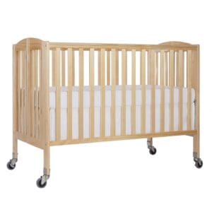 A wooden crib with wheels and white sheets.