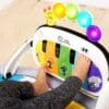 A baby playing with the piano toy on the floor.