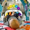 A baby laying in a chair with toys on it.