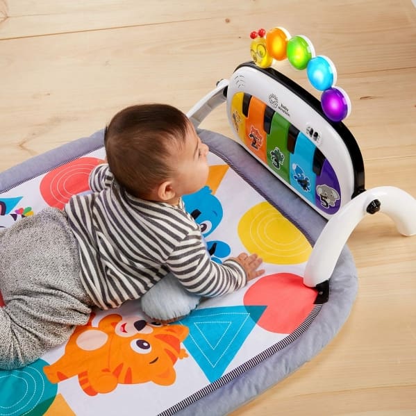 A baby is laying on the floor playing with toys.