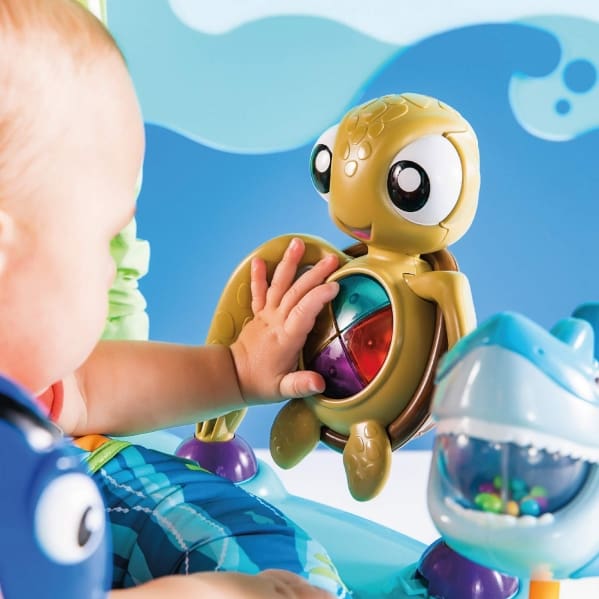 A baby playing with a toy turtle in the water.