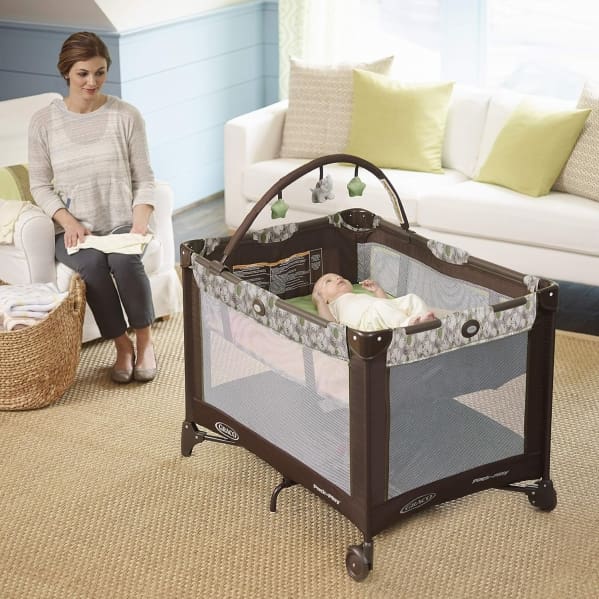 A woman is sitting in front of a baby crib.