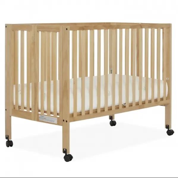 A wooden crib with wheels and white sheets.