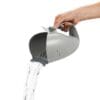 A person pouring water from a gray pitcher.