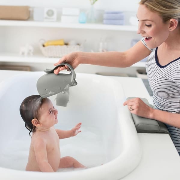 A woman is washing a baby in the sink